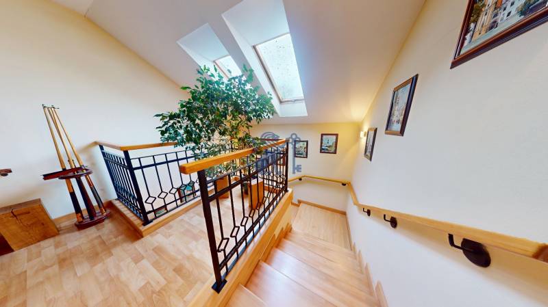 Veľkometrážny dom s wellness, bazénom a investičným potenciálom - Schodisko rodinného domu s podlahou s dreveným dekorom, obrazmi a dekoratívnym zábradlím.