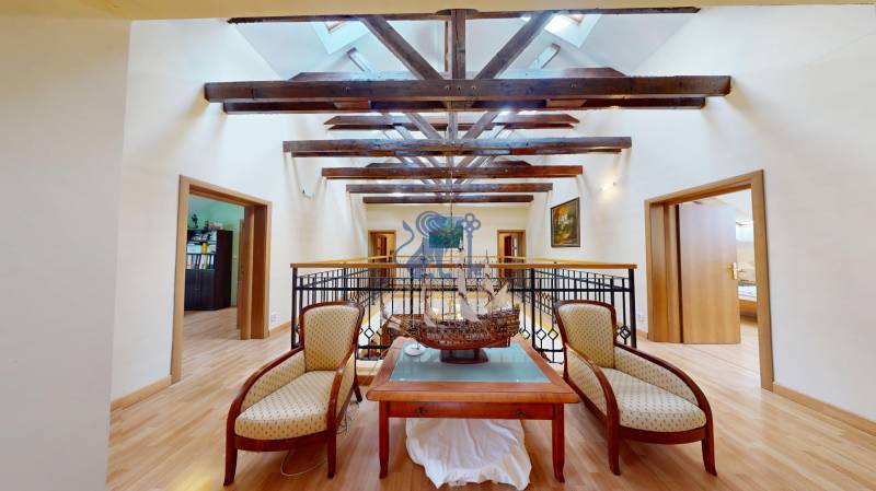 Veľkometrážny dom s wellness, bazénom a investičným potenciálom - Podkrovný priestor v rodinnom dome s dekoratívnou loďou, sedacím kútom a podlahou s dreveným dekorom.