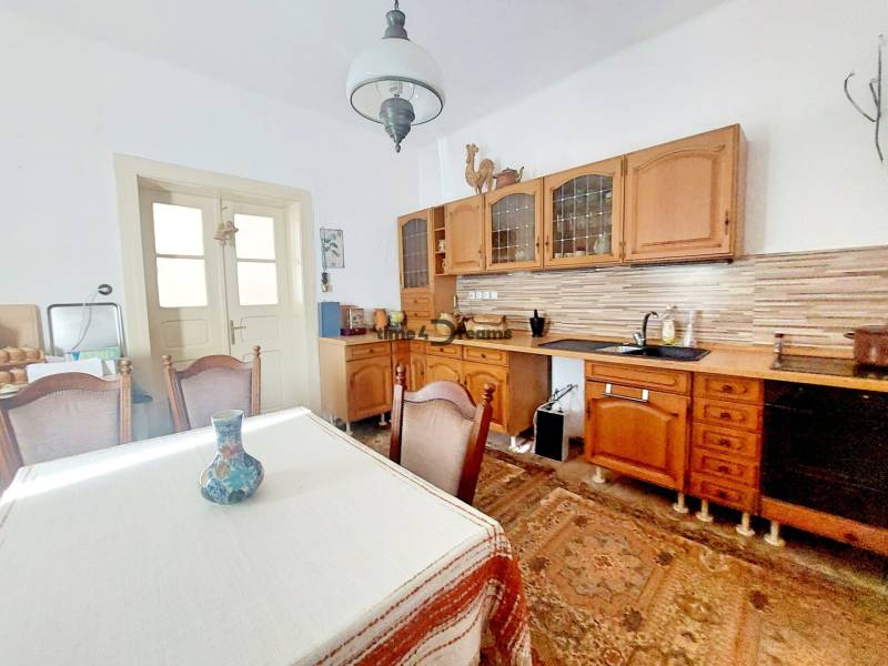 NA PREDAJ rodinný dom - Lehota nad Rimavicou - Kuchyňa v rodinnom dome s dreveným nábytkom, stolom a dekoračnou vázou.