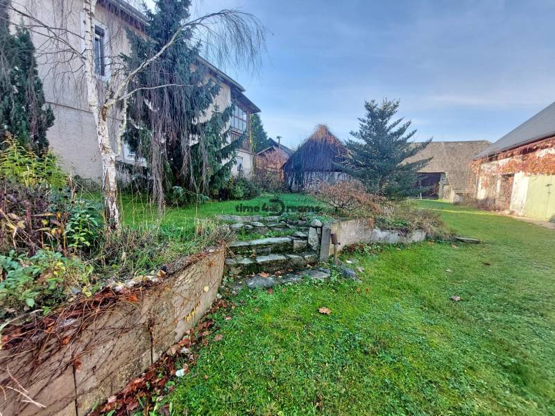 NA PREDAJ rodinný dom - Lehota nad Rimavicou - Dvor s rodinným domom, trávnik, stromy a schodisko v prírodnom prostredí.