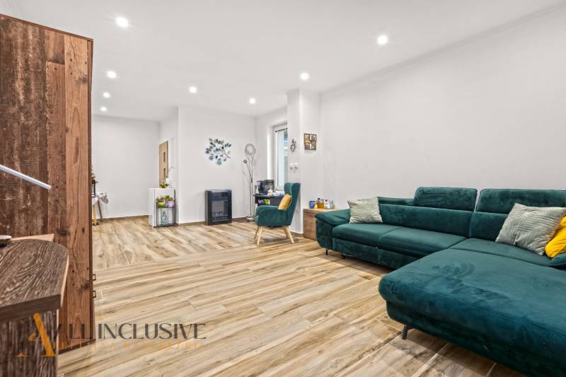 NA PREDAJ 4-IZBOVÝ RODINNÝ DOM V KOLÁROVE - Obývacia izba v rodinnom dome s podlahou v drevenom dekore a zeleným nábytkom.