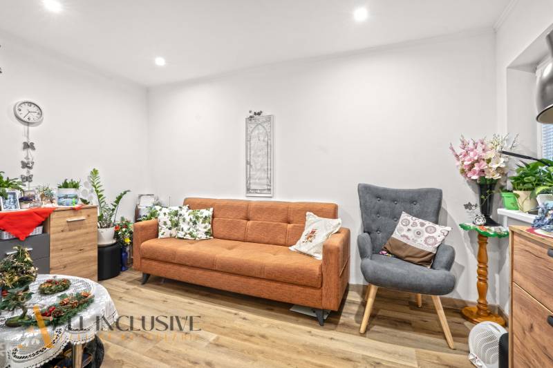 NA PREDAJ 4-IZBOVÝ RODINNÝ DOM V KOLÁROVE - Obývacia izba v rodinnom dome s pohovkou, kreslom a podlahou s dreveným dekorom.