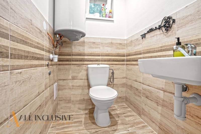 NA PREDAJ 4-IZBOVÝ RODINNÝ DOM V KOLÁROVE - Kúpeľňové zariadenie v rodinnom dome s toaletou a podlahou s dreveným dekorom.