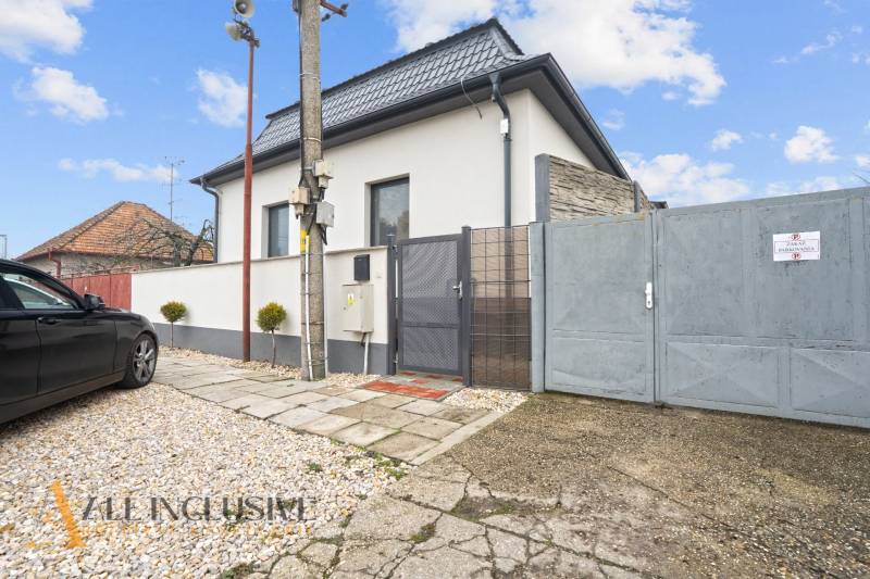 NA PREDAJ 4-IZBOVÝ RODINNÝ DOM V KOLÁROVE - Rodinný dom v Kolárove so sivou strechou, parkovaním a kovovou bránou.