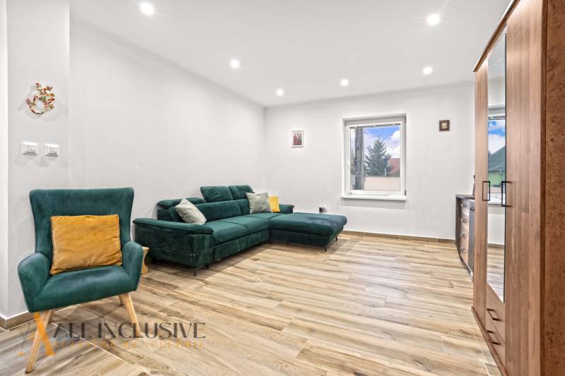 NA PREDAJ 4-IZBOVÝ RODINNÝ DOM V KOLÁROVE - Obývacia izba v rodinnom dome s pohodlnou zelenou sedačkou a podlahou s dreveným dekorom.