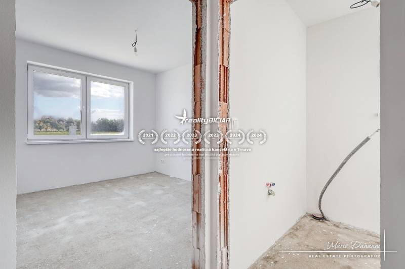 Novostavba 4-izbového rodinného domu v obci Slov.Nová Ves - Prázdna izba s veľkým oknom a neopravenými stenami v rodinnom dome.
