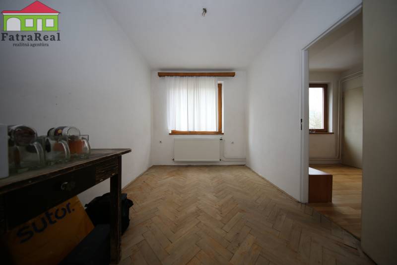 3-izb. byt v rekonštrukcii, Ľubochňa okres Ružomberok - Izba v 3-izbovom byte s podlahou s dreveným dekorom, viditeľné dva okná a radiátor.