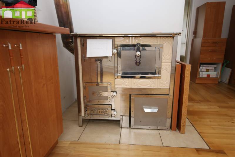 3-izb. byt v rekonštrukcii, Ľubochňa okres Ružomberok - Kachľová pec v 3-izbovom byte s podlahou s dreveným dekorom a dreveným nábytkom.