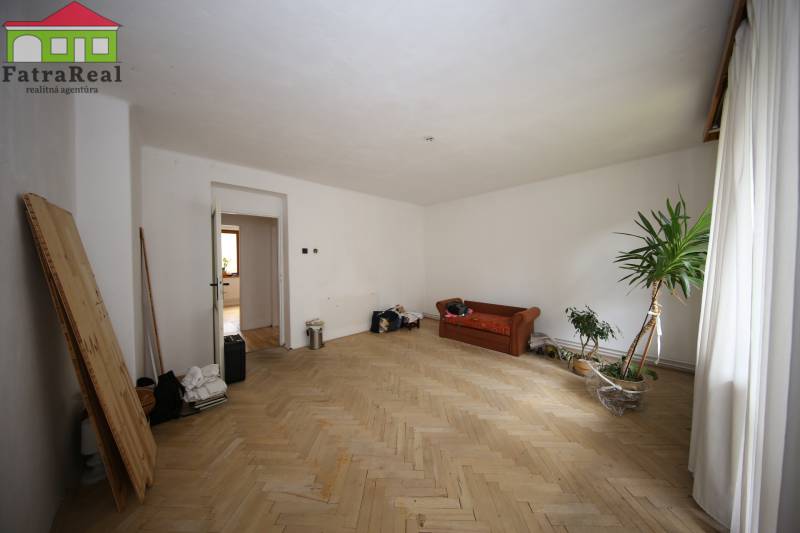 3-izb. byt v rekonštrukcii, Ľubochňa okres Ružomberok - Obývacia izba s pohovkou, podlahou s dreveným dekorom a izbovou rastlinou v 3-izbovom byte.