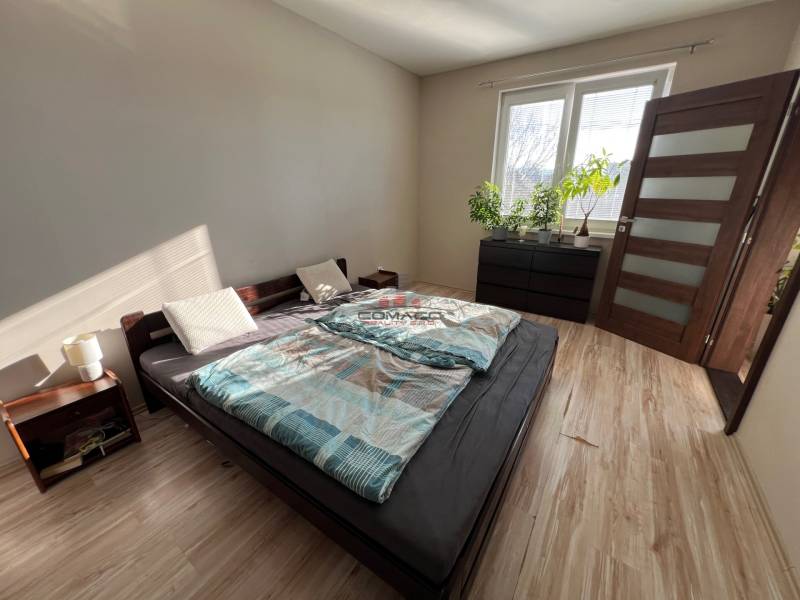 2iz byt v novostavbe Hlohovec Zľava!!! - Spálňa s posteľou, nočným stolíkom a podlahou s dreveným dekorom v 2-izbovom byte.