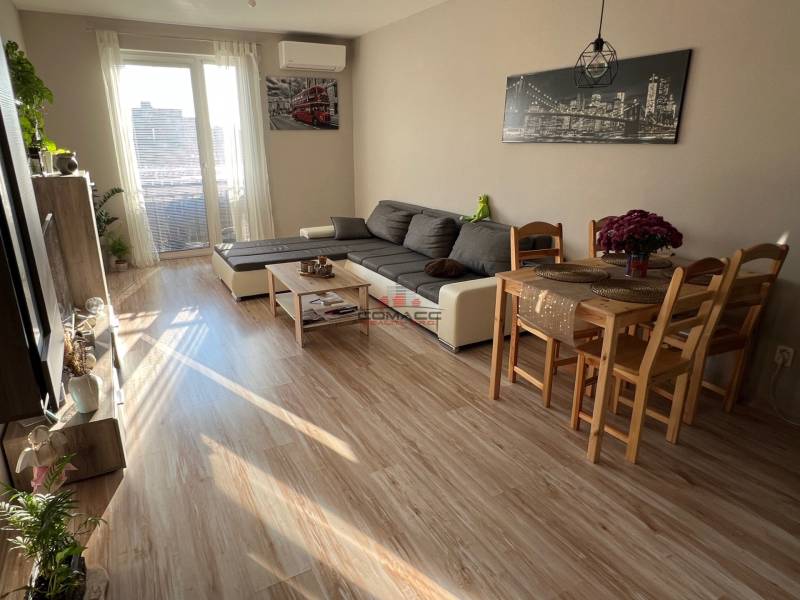 2iz byt v novostavbe Hlohovec Zľava!!! - Obývacia izba s pohovkou, jedálenským stolom a podlahou s dreveným dekorom v 2-izbovom byte.