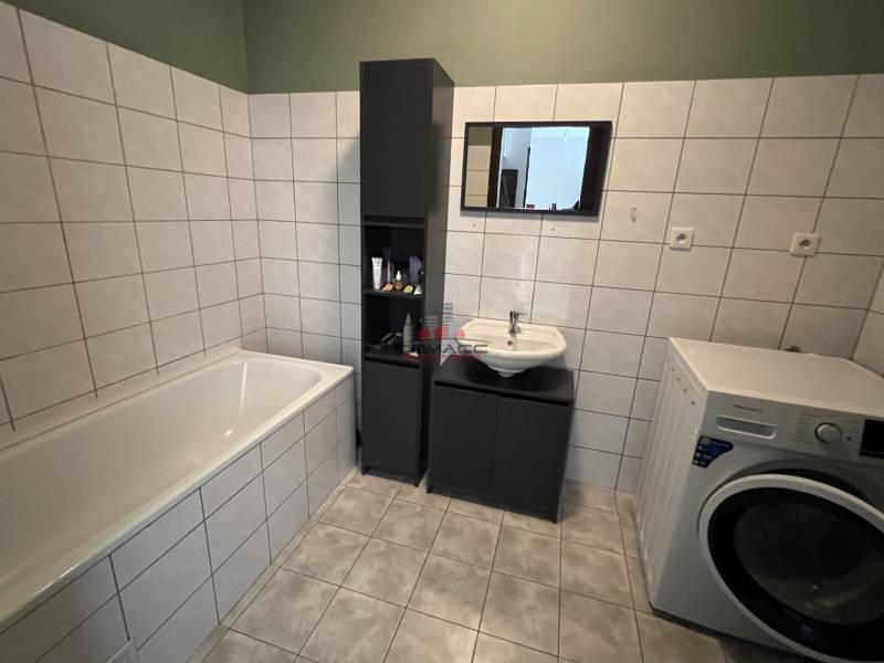 2iz byt v novostavbe Hlohovec Zľava!!! - Kúpeľňa v 2-izbovom byte s vaňou, umývadlom a práčkou, obklopená bielymi kachličkami.