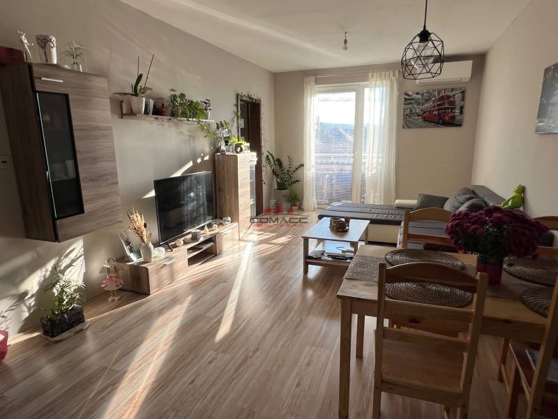 2iz byt v novostavbe Hlohovec Zľava!!! - Obývacia izba v 2-izbovom byte s podlahou s dreveným dekorom a pohodlným sedením.