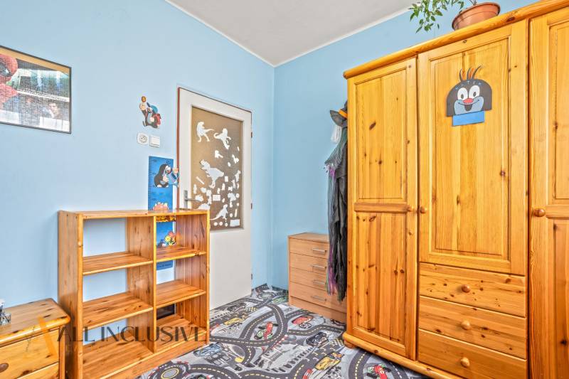 NA PREDAJ 6-IZBOVÝ RD S VEĽKÝM POZOMKOM, DOLNÝ ŠTÁL - Detská izba v rodinnom dome s dreveným nábytkom, modrými stenami a hravým kobercom.