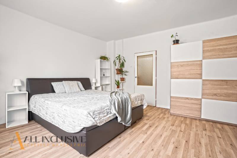 NA PREDAJ 6-IZBOVÝ RD S VEĽKÝM POZOMKOM, DOLNÝ ŠTÁL - Spálňa s posteľou, skriňou, rastlinami a podlahou s dreveným dekorom v rodinnom dome.