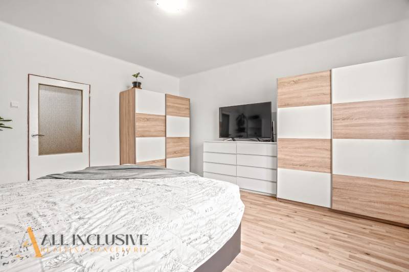 NA PREDAJ 6-IZBOVÝ RD S VEĽKÝM POZOMKOM, DOLNÝ ŠTÁL - Spálňa v rodinnom dome s televíziou, skrinkami a podlahou s dreveným dekorom.