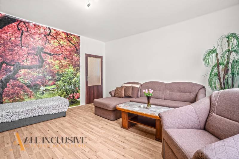 NA PREDAJ 6-IZBOVÝ RD S VEĽKÝM POZOMKOM, DOLNÝ ŠTÁL - Obývacia izba s pohovkou, fototapetou stromov a podlahou s dreveným dekorom v rodinnom dome.