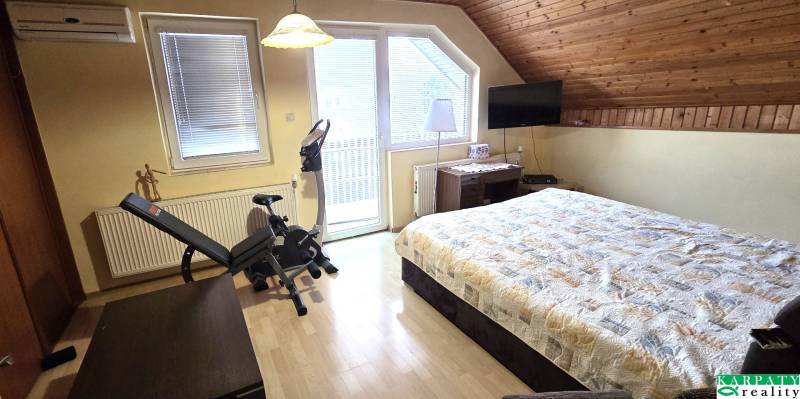 Na predaj 2 rodinné domy vhodné na bývanie i podnikanie, Trnava! - Spálňa v rodinnom dome s posteľou, rotopedom a podlahou s dreveným dekorom.