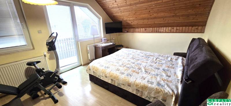 Na predaj 2 rodinné domy vhodné na bývanie i podnikanie, Trnava! - Spálňa v rodinnom dome s cvičebným bicyklom a podlahou s dreveným dekorom.