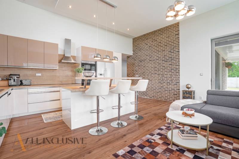 NA PREDAJ NADŠTANDARDNÁ 4-IZB. NOVOSTAVBA, DUN. KLÁTOV - Kuchyňa s ostrovčekom a barovými stoličkami v rodinnom dome, tehlová stena.