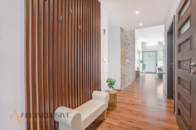 NA PREDAJ NADŠTANDARDNÁ 4-IZB. NOVOSTAVBA, DUN. KLÁTOV - Chodba rodinného domu s drevenou stenou, svetlou lavicou a dekoratívnymi prvkami.