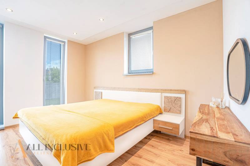 NA PREDAJ NADŠTANDARDNÁ 4-IZB. NOVOSTAVBA, DUN. KLÁTOV - Svetlá spálňa s drevenou podlahou a žltou prikrývkou v rodinnom dome.