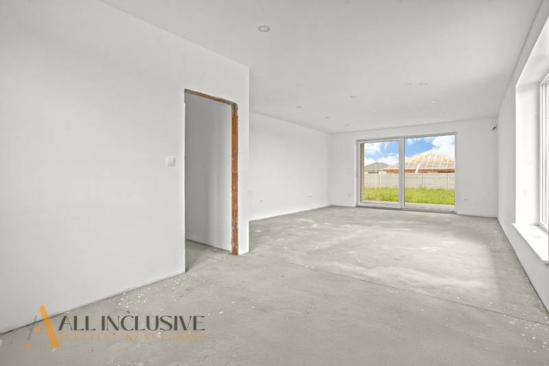 NA PREDAJ 4-IZBOVÁ NOVOSTAVBA, POVODA - Prázdna izba s betónovou podlahou v rodinnom dome má veľké okno do záhrady.