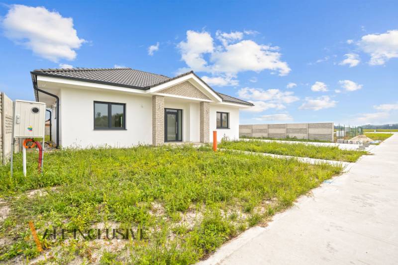 NA PREDAJ 4-IZBOVÁ NOVOSTAVBA, POVODA - Rodinný dom na ulici Povoda v Dunajskej Strede obklopený zelenou lúkou a plotom.