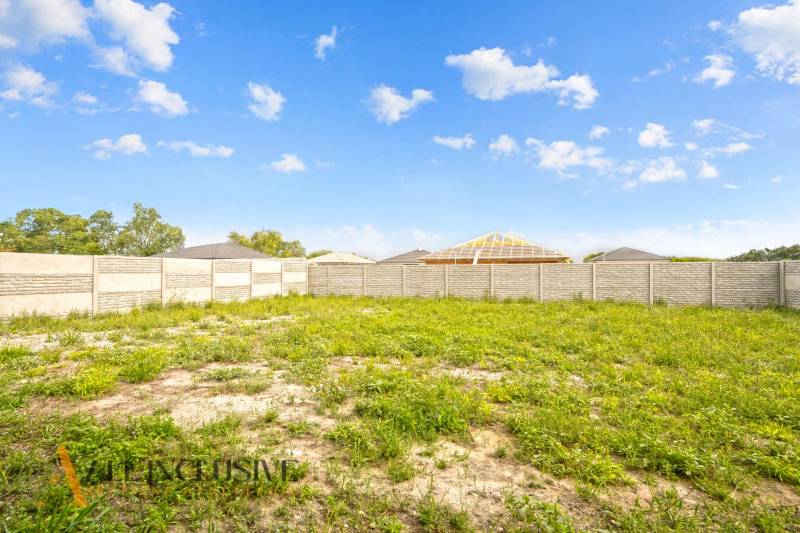 NA PREDAJ 4-IZBOVÁ NOVOSTAVBA, POVODA - Pozemok pri rodinných domoch na ulici Povoda, Dunajská Streda s plotom a trávou.