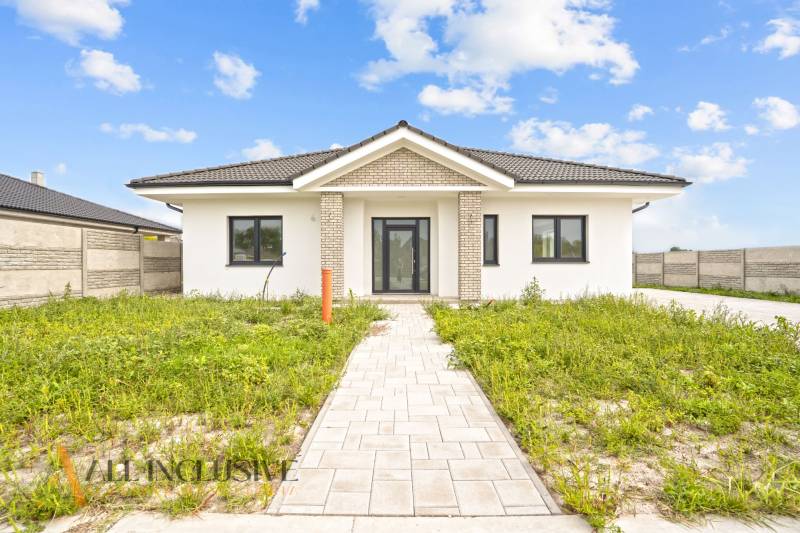 NA PREDAJ 4-IZBOVÁ NOVOSTAVBA, POVODA - Rodinný dom na ulici Povoda v Dunajskej Strede s trávnikom a dlaždicovým chodníkom.