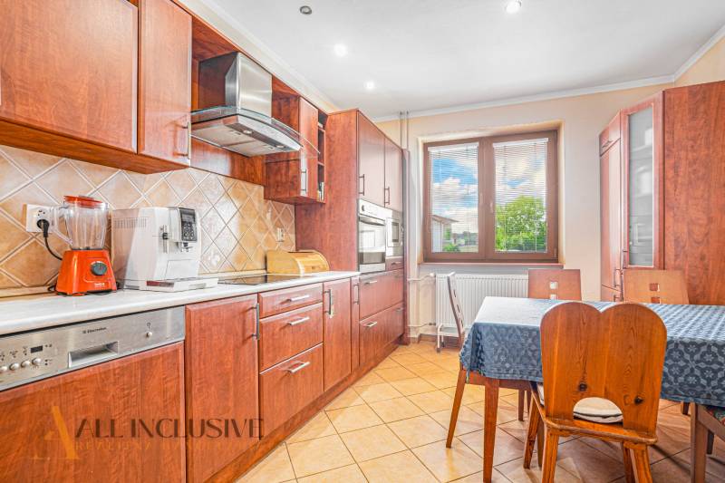 NA PREDAJ 5-IZBOVÝ POSCH. RODINNÝ DOM, DUNAJSKÁ STREDA - Kuchyňa v rodinnom dome s dreveným nábytkom, spotrebičmi a jedálenským stolom.