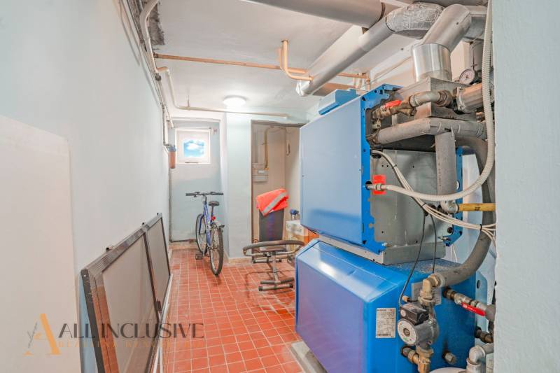 NA PREDAJ 5-IZBOVÝ POSCH. RODINNÝ DOM, DUNAJSKÁ STREDA - Kotolňa s modrobielym kotlom, bicyklom a červenohnedou podlahou v rodinnom dome.