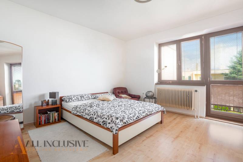 NA PREDAJ 5-IZBOVÝ POSCH. RODINNÝ DOM, DUNAJSKÁ STREDA - Svetlá spálňa s veľkým oknom, posteľou a kreslom v rodinnom dome.