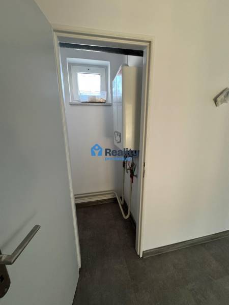 Prenájom obchod/kancelária NP nová kompletná rekonštrukcia, centrum PB - Interiér obchodných priestorov s moderným kotlom a malým oknom v stene.