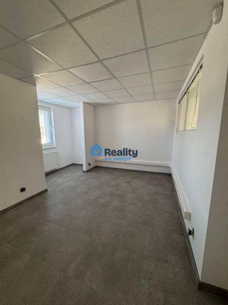 Prenájom obchod/kancelária NP nová kompletná rekonštrukcia, centrum PB - Prázdne obchodné priestory s oknom, bielymi stenami a sivou podlahou.