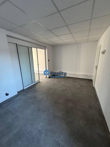 Prenájom obchod/kancelária NP nová kompletná rekonštrukcia, centrum PB - Obchodné priestory s posuvnými dverami a dlažbou. Neutrálna a svetlá miestnosť.