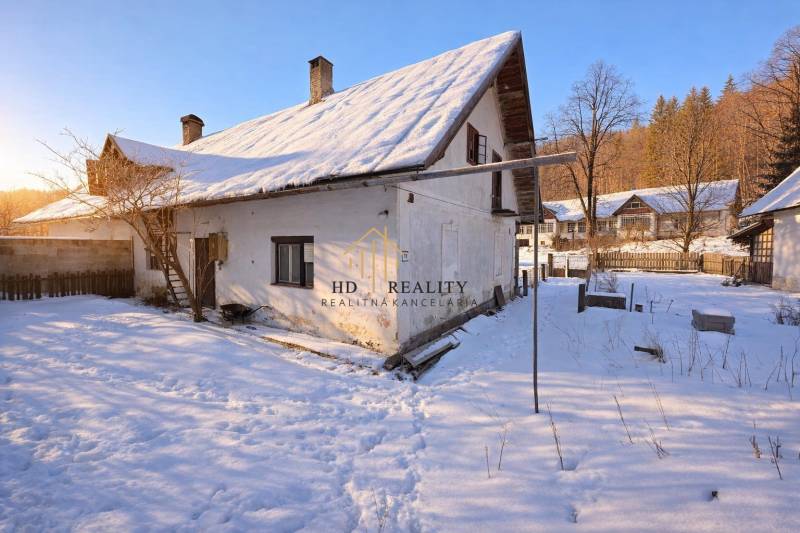 Predaj, rodinný dom Sliačany, Donovaly - Zasnežený rodinný dom v Donovaloch obklopený stromami a modrou oblohou.