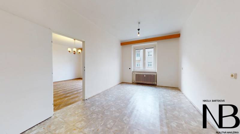 Na predaj 2,5 izbový byt v pôvodnom stave, 79 m2, Pod Sokolice, TN - Priestranná miestnosť v 2-izbovom byte s oknom a podlahou s dreveným dekorom.