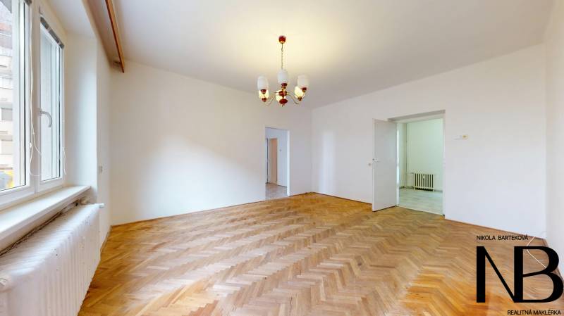 Na predaj 2,5 izbový byt v pôvodnom stave, 79 m2, Pod Sokolice, TN - Izba 2-izbového bytu s lustrom a podlahou s dreveným dekorom.