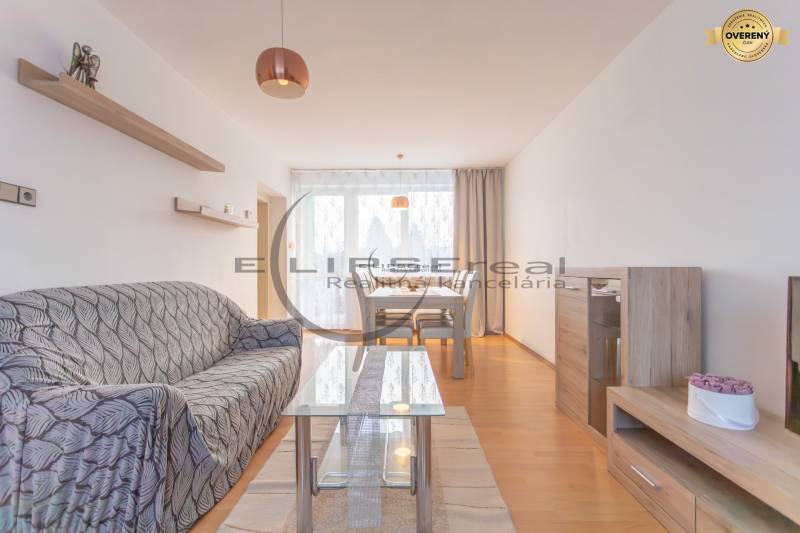 NA PREDAJ priestranný 4-izbový rodinný dom v Plaveckom Štvrtku - Interiér rodinného domu so sedačkou, stolom a podlahou s dreveným dekorom.