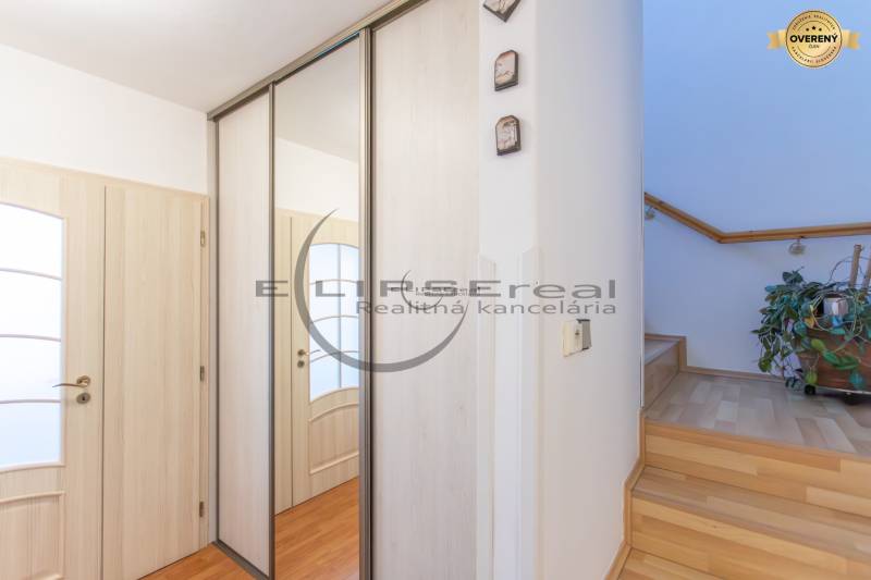 NA PREDAJ priestranný 4-izbový rodinný dom v Plaveckom Štvrtku - Predsieň rodinného domu so zrkadlovou skriňou, dverami a schodiskom s podlahou s dreveným dekorom.