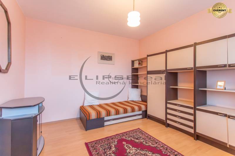 NA PREDAJ priestranný 4-izbový rodinný dom v Plaveckom Štvrtku - Izba s posteľou a nábytkom, podlaha s dreveným dekorom a svetloružové steny.