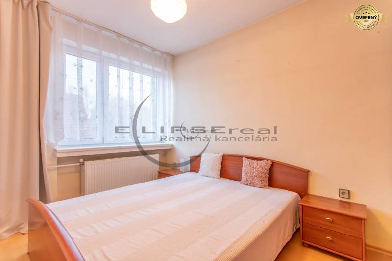 NA PREDAJ priestranný 4-izbový rodinný dom v Plaveckom Štvrtku - Spálňa v rodinnom dome s posteľou, nočným stolíkom a podlahou s dreveným dekorom.