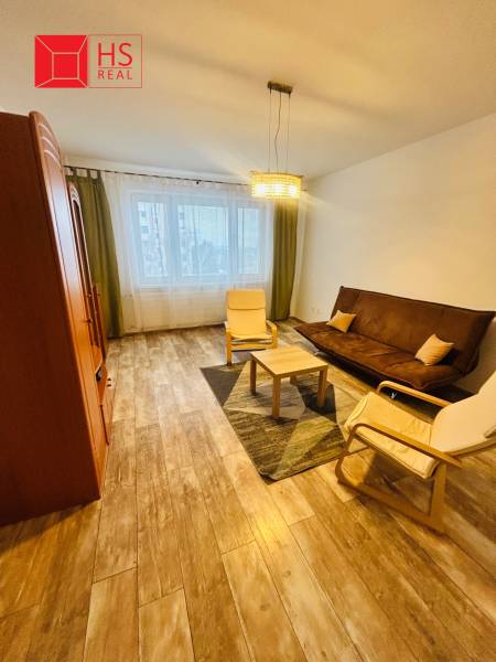 Prenajom 3 izb. bytu na Vajanskeho v NZ - Obývacia izba v 3-izbovom byte so sedačkou a podlahou s dreveným dekorom.