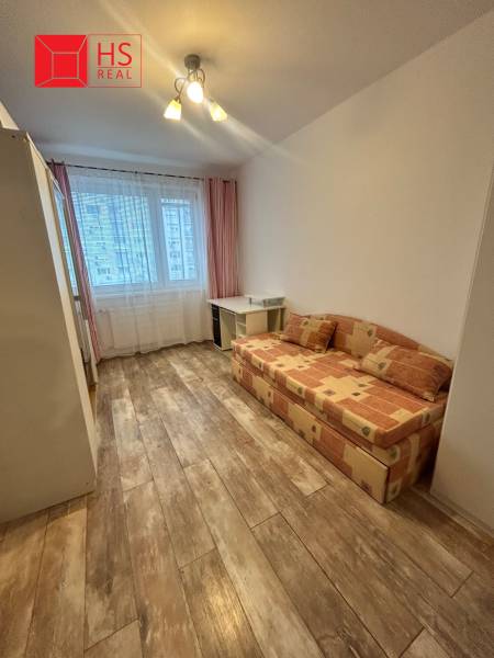 Prenajom 3 izb. bytu na Vajanskeho v NZ - Izba v 3-izbovom byte s podlahou s dreveným dekorom a rozkladacou pohovkou.