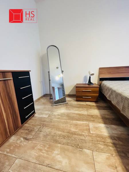 Prenajom 3 izb. bytu na Vajanskeho v NZ - Spálňa v 3-izbovom byte, podlaha s dreveným dekorom, nábytok z tmavého dreva.