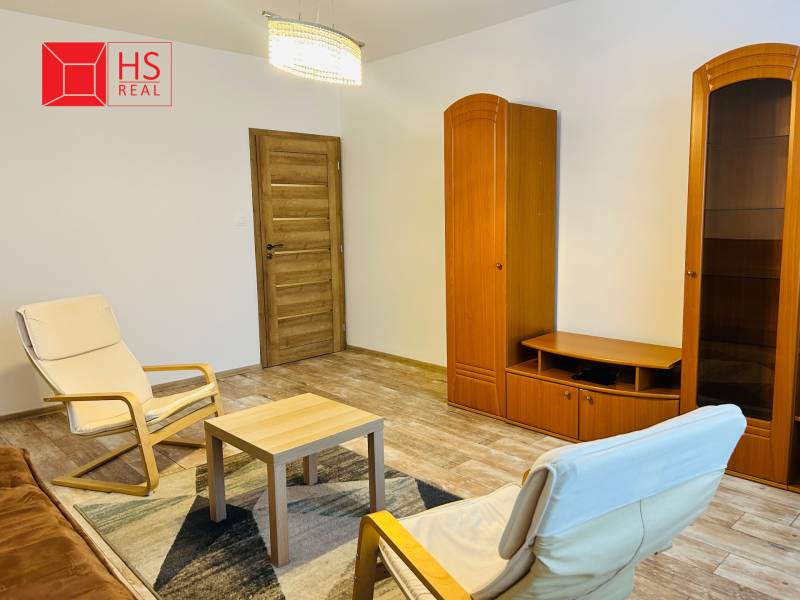 Prenajom 3 izb. bytu na Vajanskeho v NZ - Obývacia izba s nábytkom a podlahou s dreveným dekorom v 3-izbovom byte.