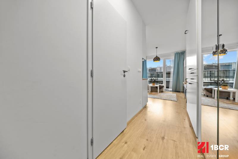 ZARIADENÝ 1-IZBOVÝ BYT, SLNEČNICE – IDEÁLNA INVESTÍCIA AJ BÝVANIE - Interiér 1-izbového bytu s podlahou s dreveným dekorom a svetlým zariadením.