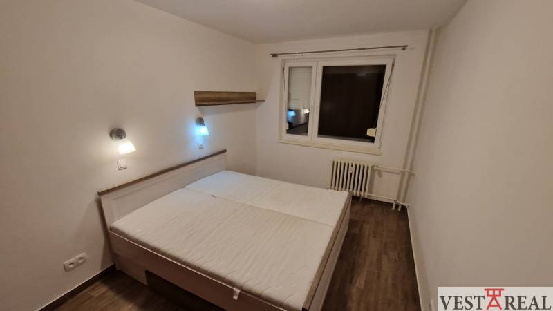 Na prenájom zariadený 3 izbový byt s balkónom Galanta- Mierová - Spálňa v 3-izbovom byte s posteľou, nočnými lampami a podlahou s dreveným dekorom.