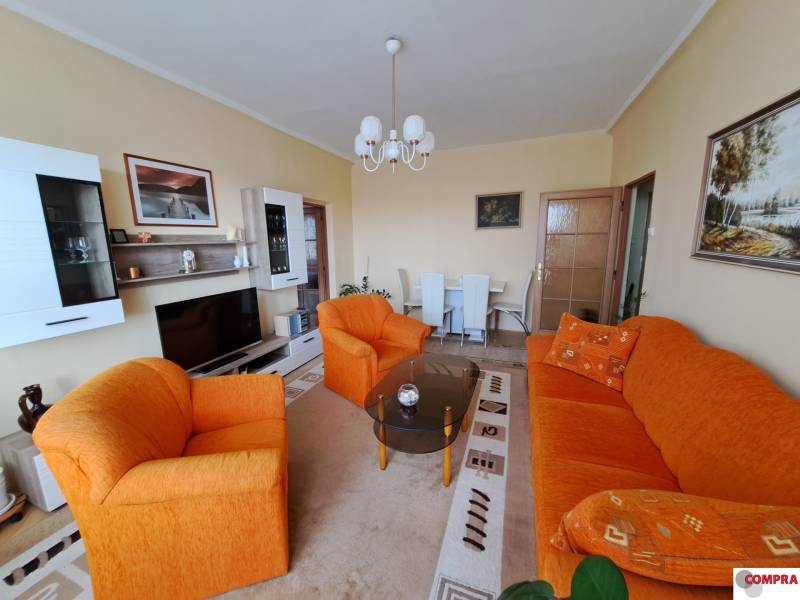 Pekný 2 izbový byt na Jadrovej ul. - Obývacia izba v 2-izbovom byte s oranžovou sedačkou a televízia.